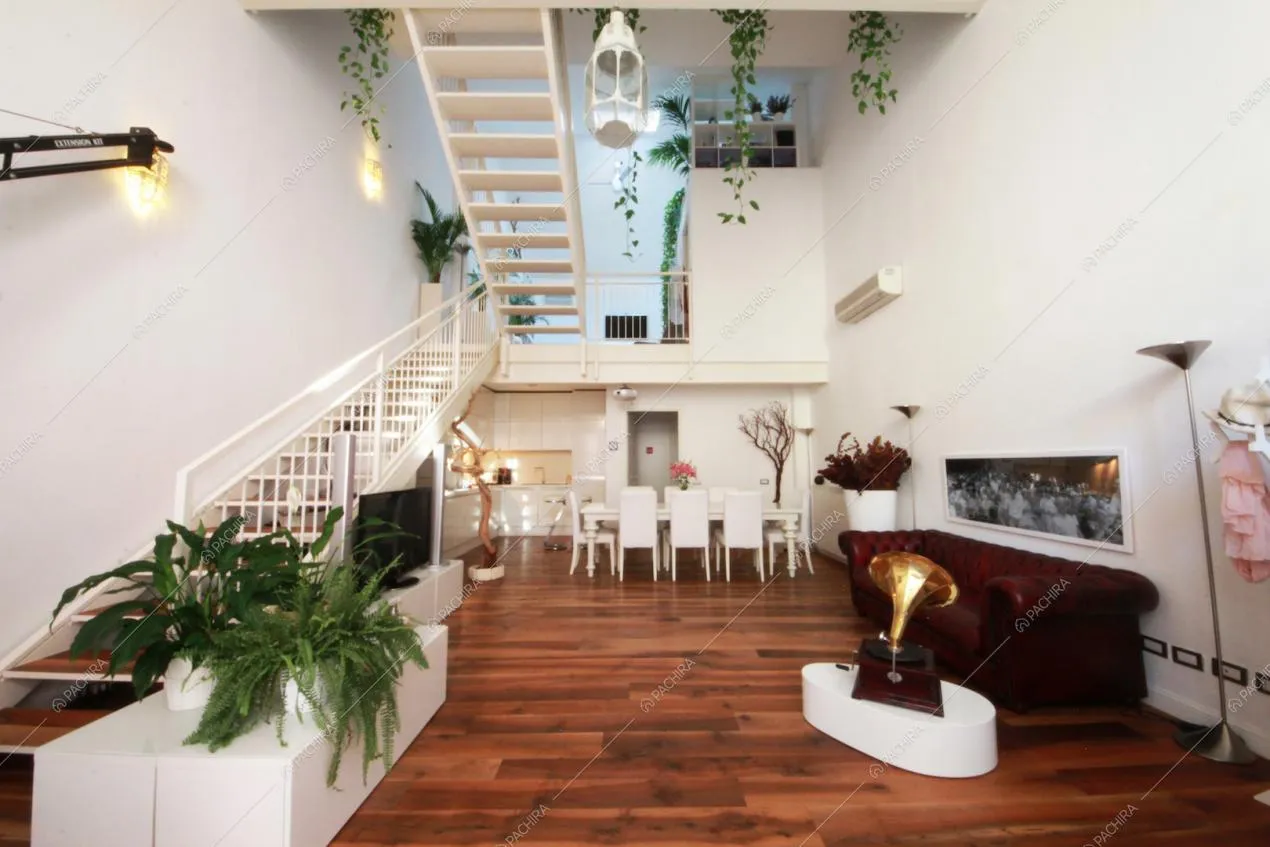 Zona living con parquet a listoni e scale bianche