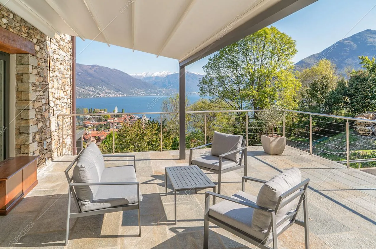 Sulla terrazza dal pavimento in pietra, veranda con salotto da esterni e vista sul lago