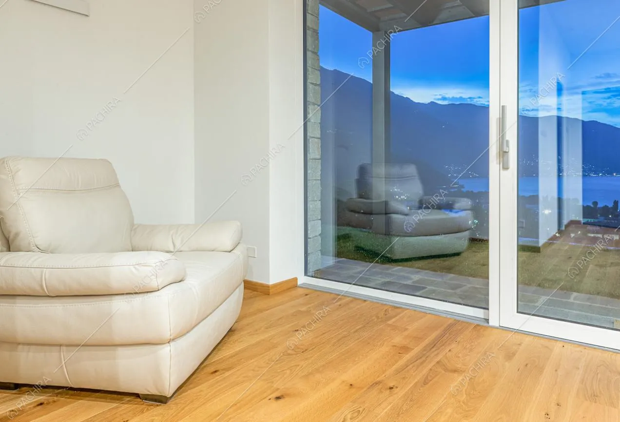 Pavimento in parquet e pareti bianche nella stanza con porta-finestra vista lago
