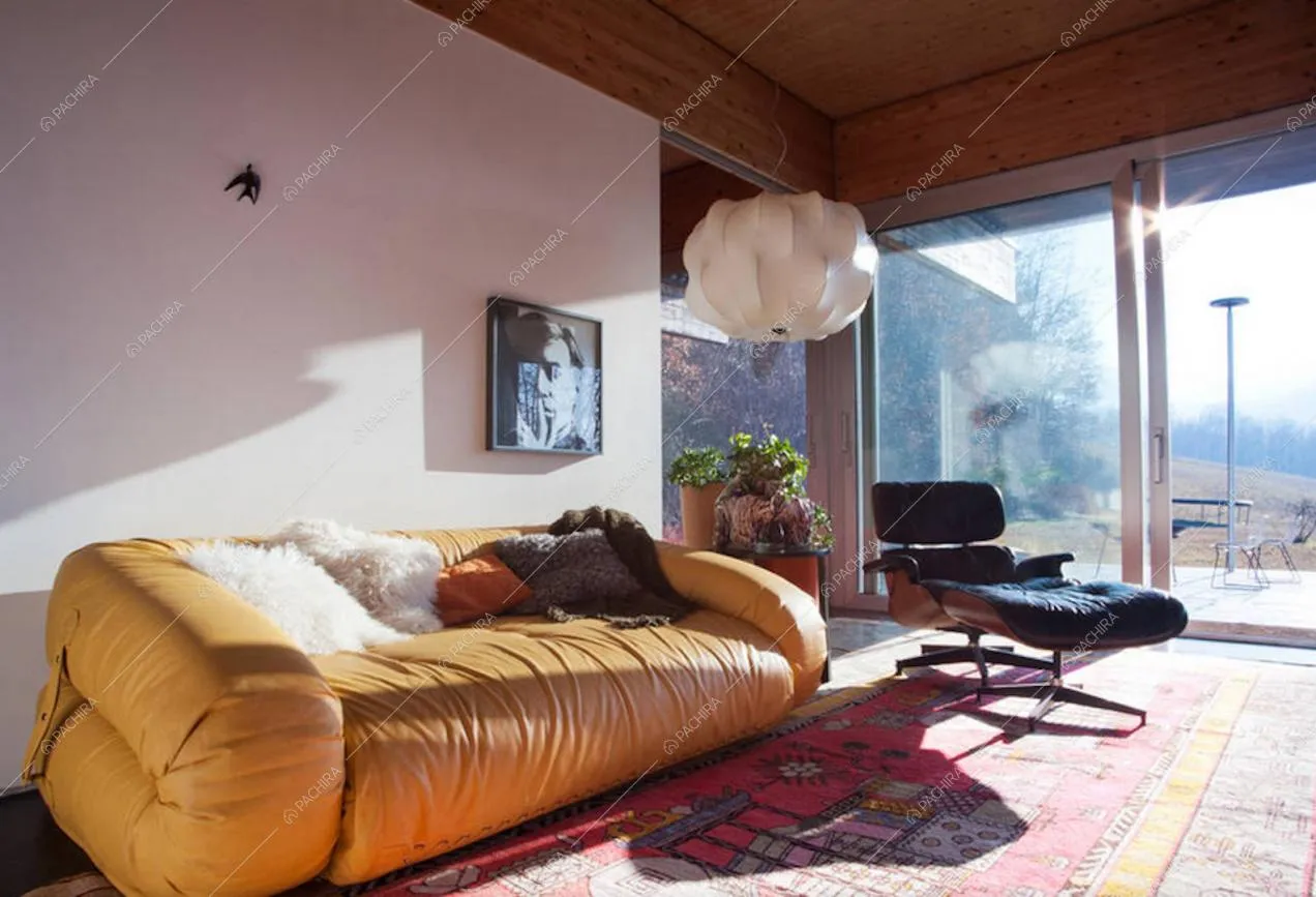 Divano giallo, lampadario di design e vetrate a parete nella zona relax