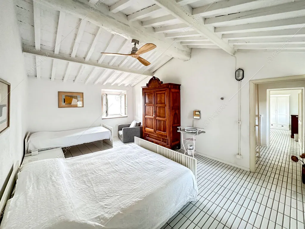 Camera da letto matrimoniale con pavimento in piastrelle bianche e vista sul corridoio