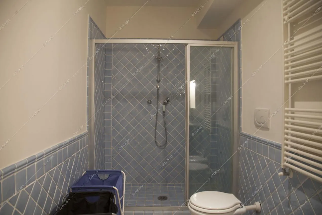 Bagno con piastrelle azzurre e box doccia