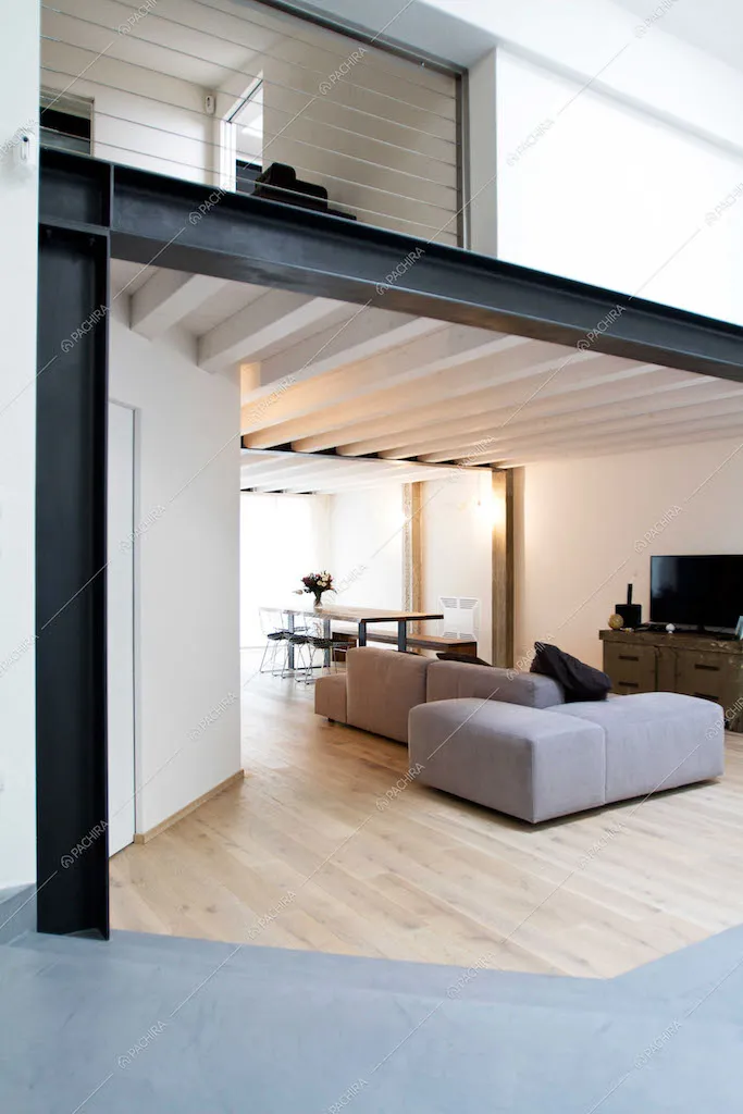 Zona living con parquet e travi a vista e scorcio sul soppalco
