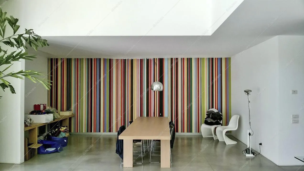 Altra visuale sulla zona living con tavolo di legno e carta da parati multicolore