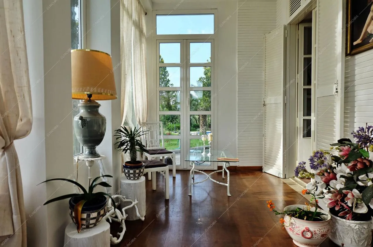 Porte finestre, pavimento in parquet e sedie con tavolino in vetro nella zona relax