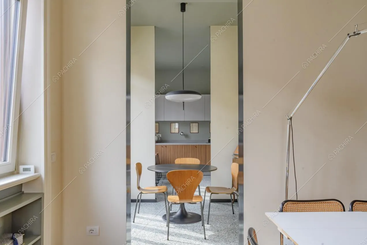Vista sul tavolo da pranzo nero con sedie di legno di design e sulla cucina a muro