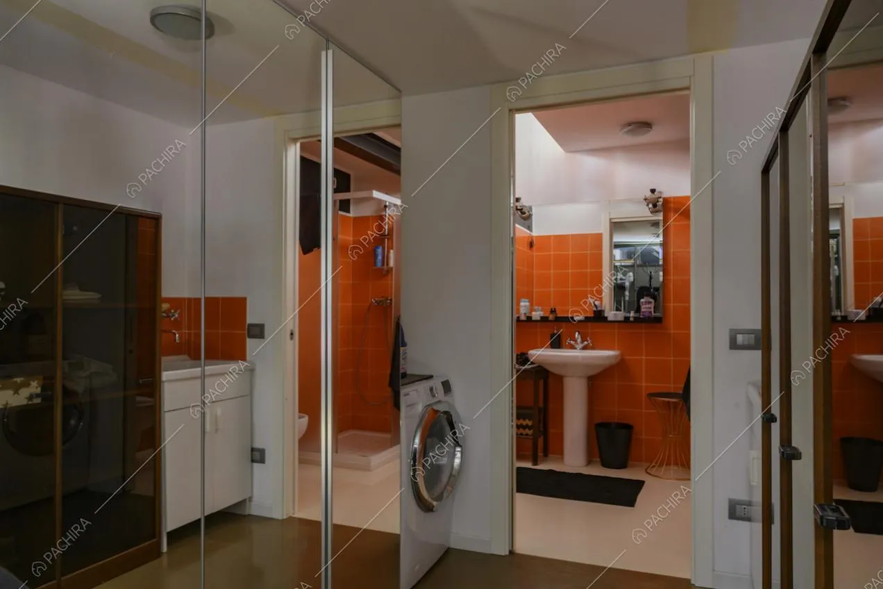 Piastrelle arancioni nel bagno e grandi specchi
