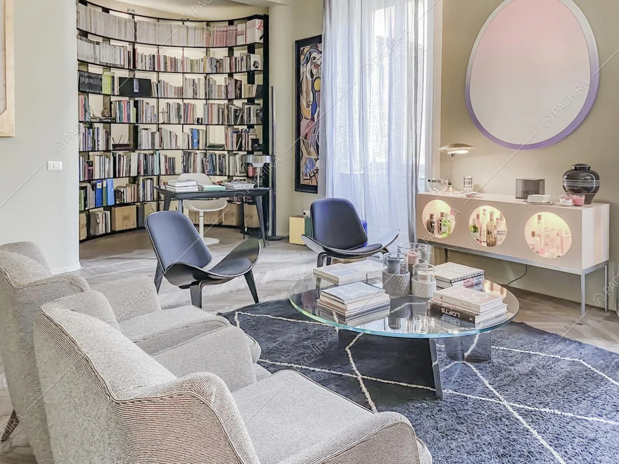 Salotto con grande libreria piena di libri, poltrone e sedie di design