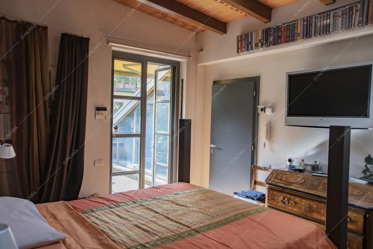 Camera da letto matrimoniale dalle pareti bianche con porte-finestre per accedere alla terrazza