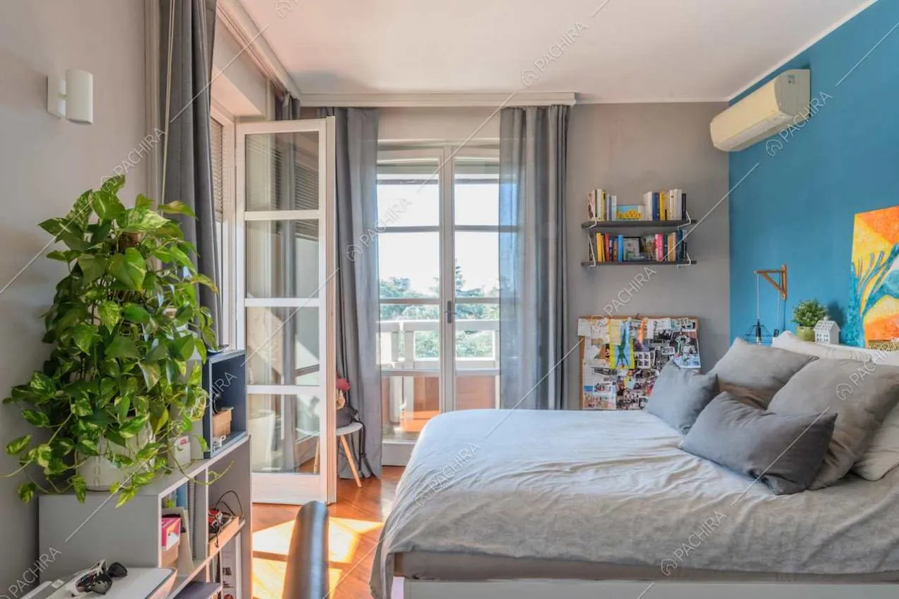 Camera da letto matrimoniale con porte-finestre e parete azzurra
