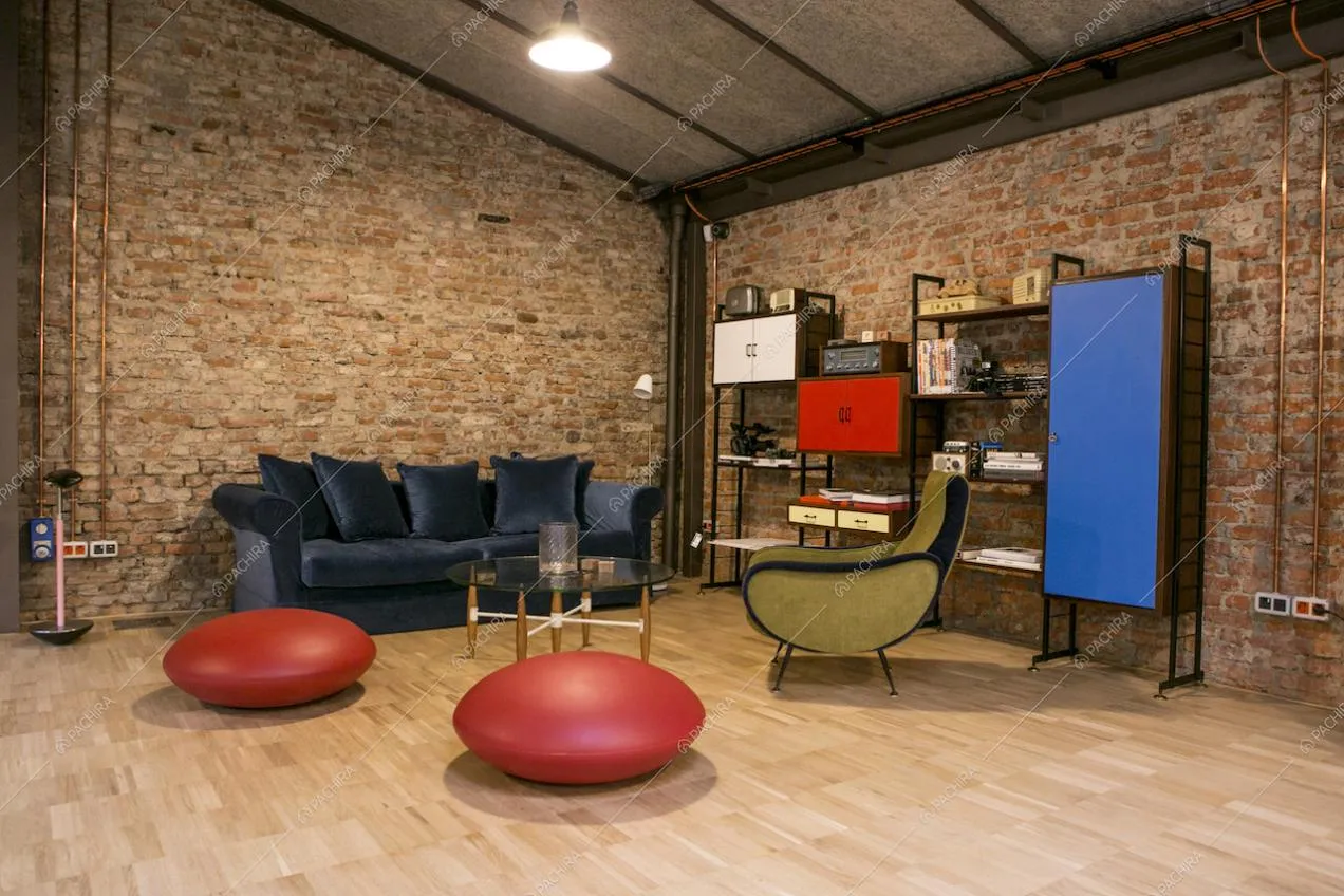 Living open space con travi a vista e pareti in mattoni