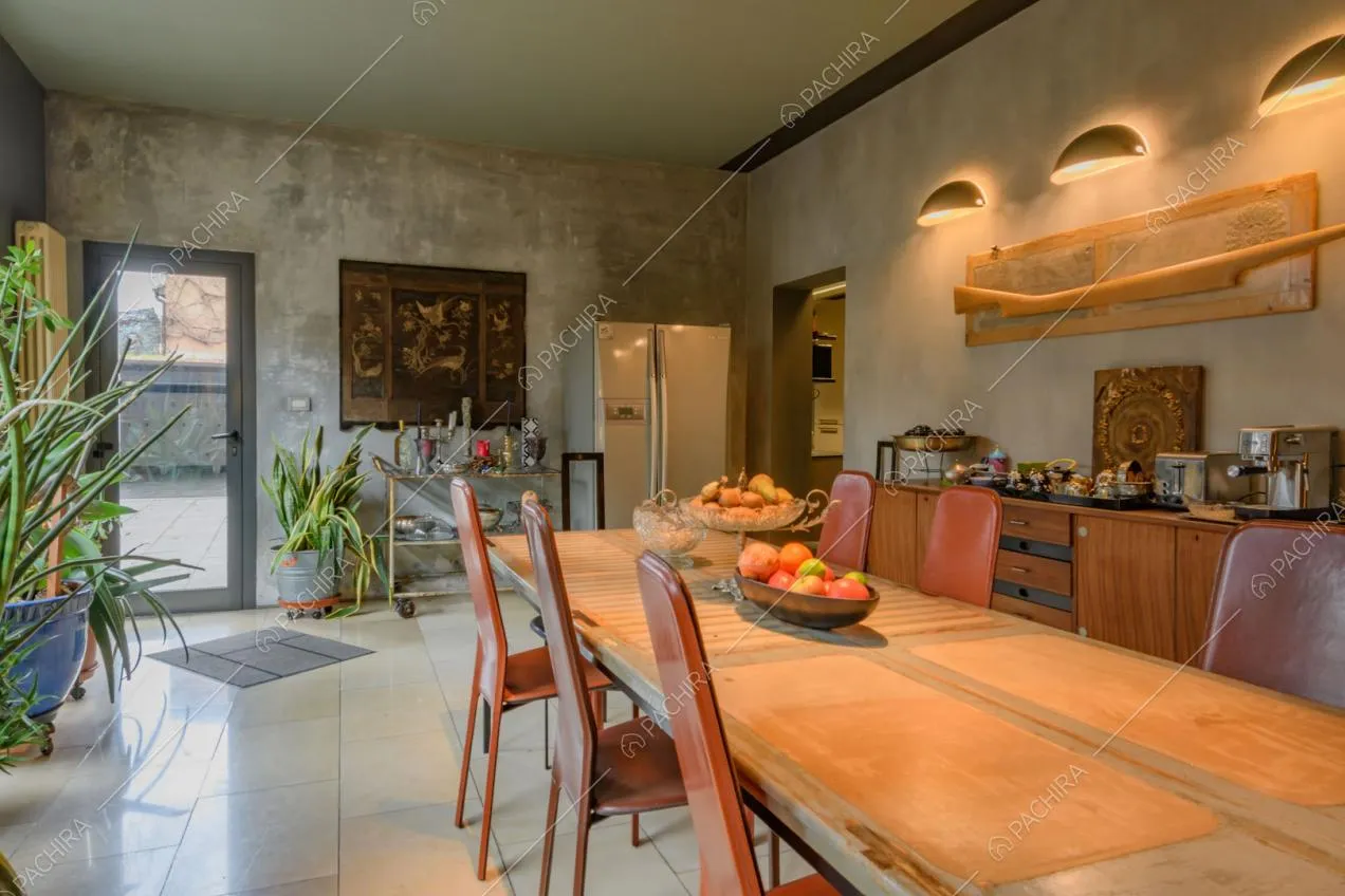 Luminosa sala da pranzo con grande tavolo, sedie rosse di design e porta-finestra