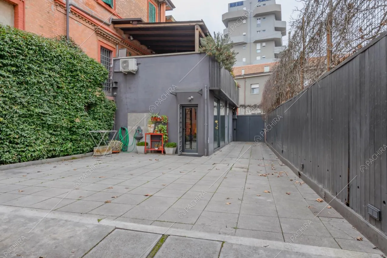 Grande cortile della location con siepe e pavimentazione in piastrelle
