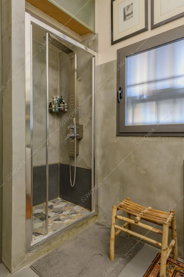 Box doccia nel bagno con pavimento e pareti in cemento lisciato