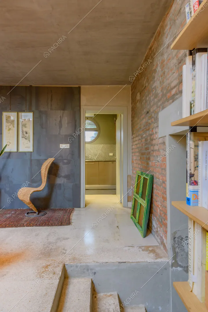 Libreria, scalini e scorcio sulla cucina dalla luminosa sala