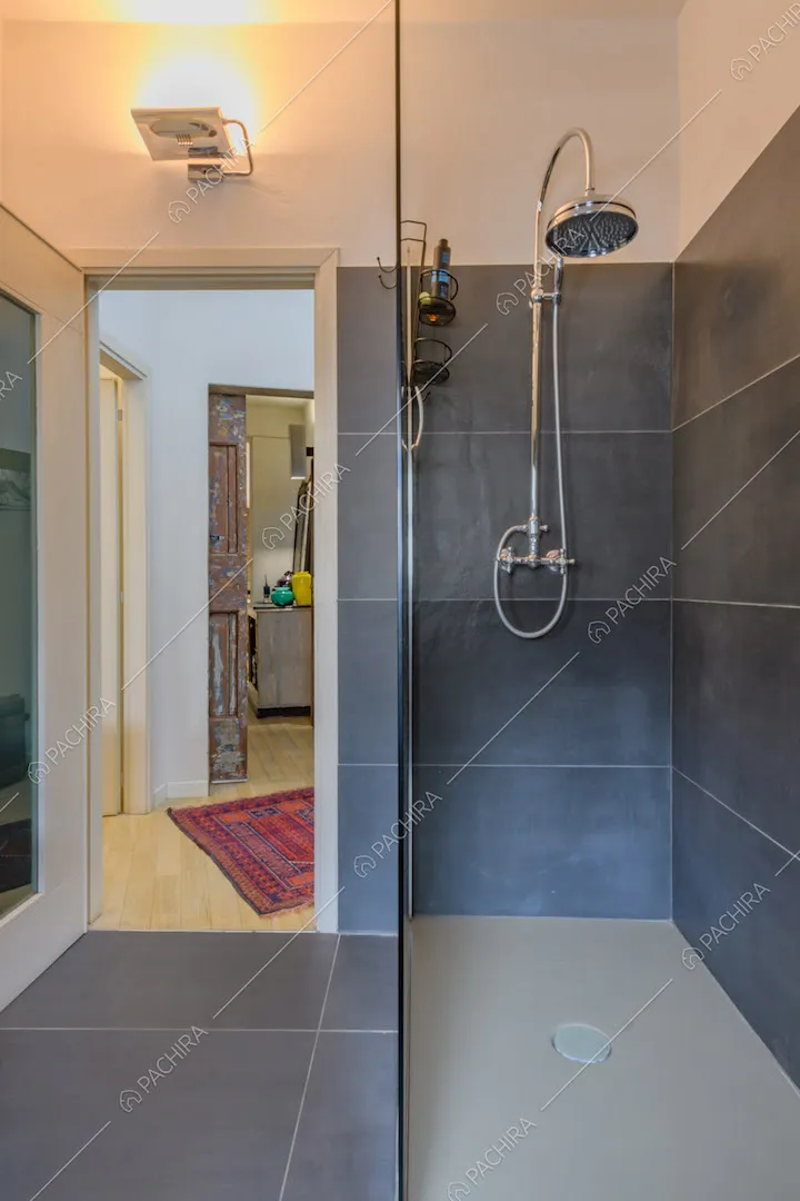 Box doccia nel bagno con pavimento e pareti in piastrelle nere