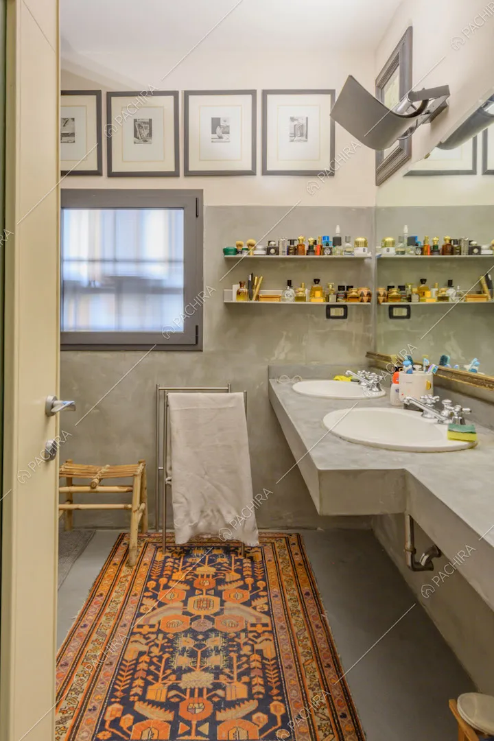 Bagno con doppio lavandino e pavimento e pareti in cemento lisciato