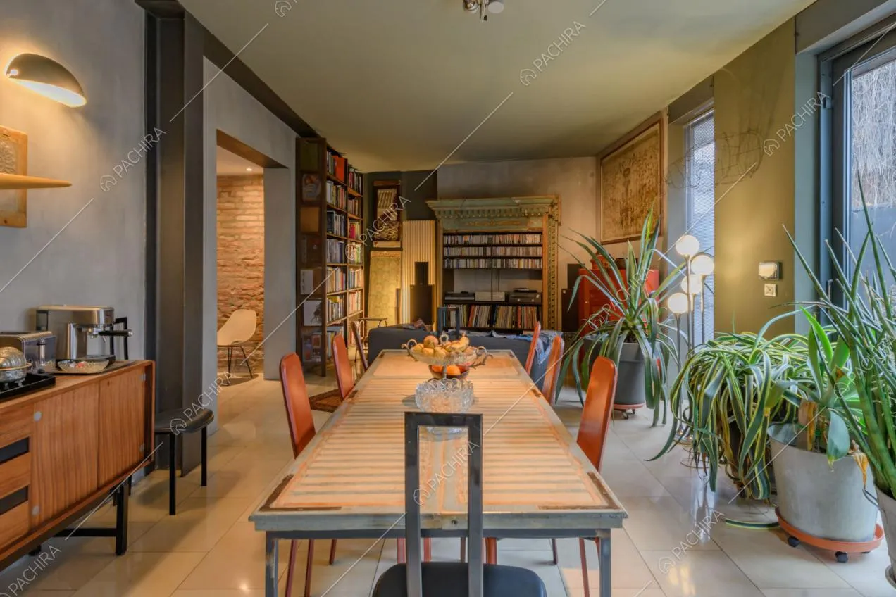 Lungo tavolo nella sala da pranzo con pareti délabré, vetrate e mobili di design
