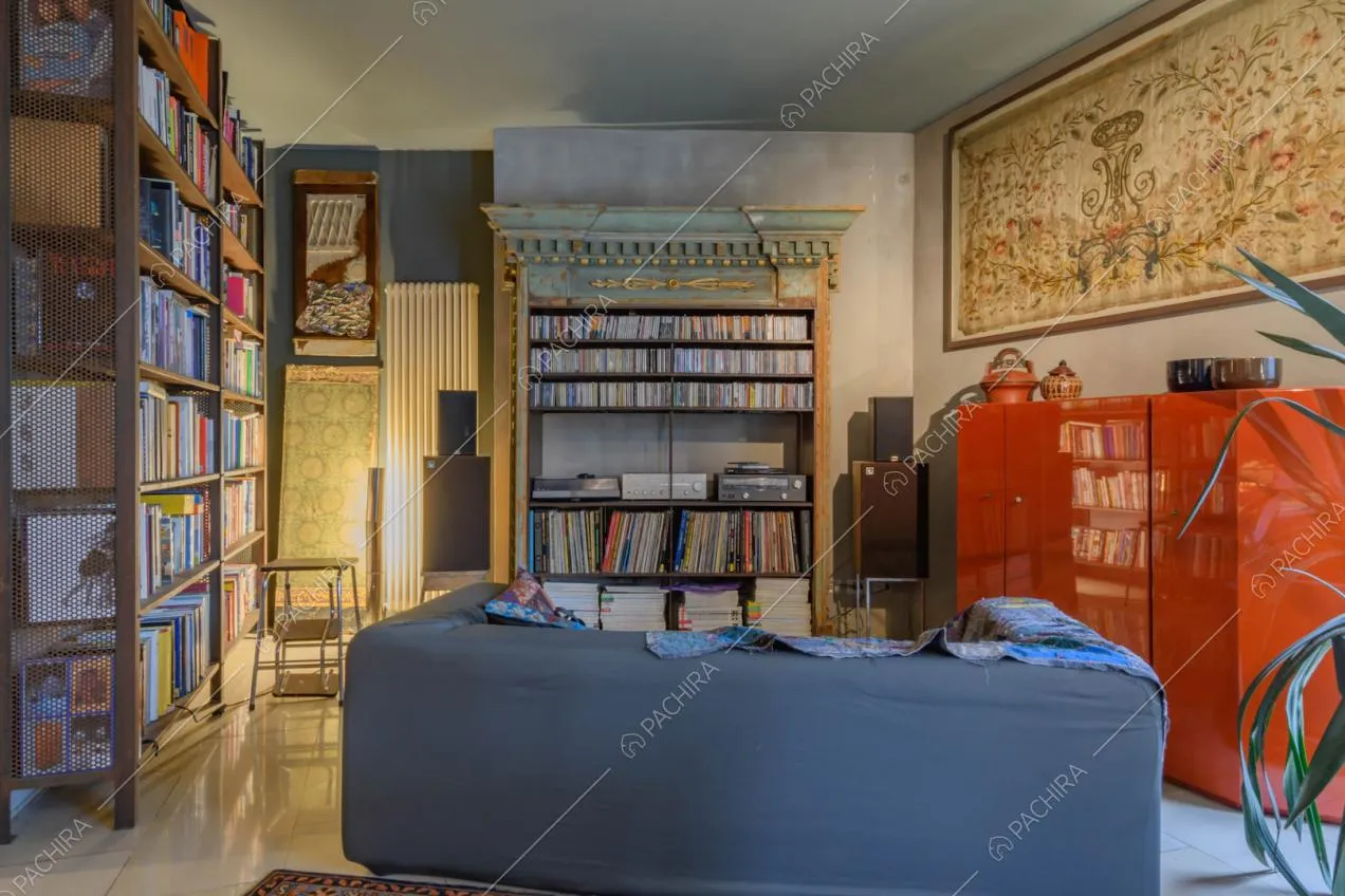 Salotto con librerie, divano nero e mobile rosso di design