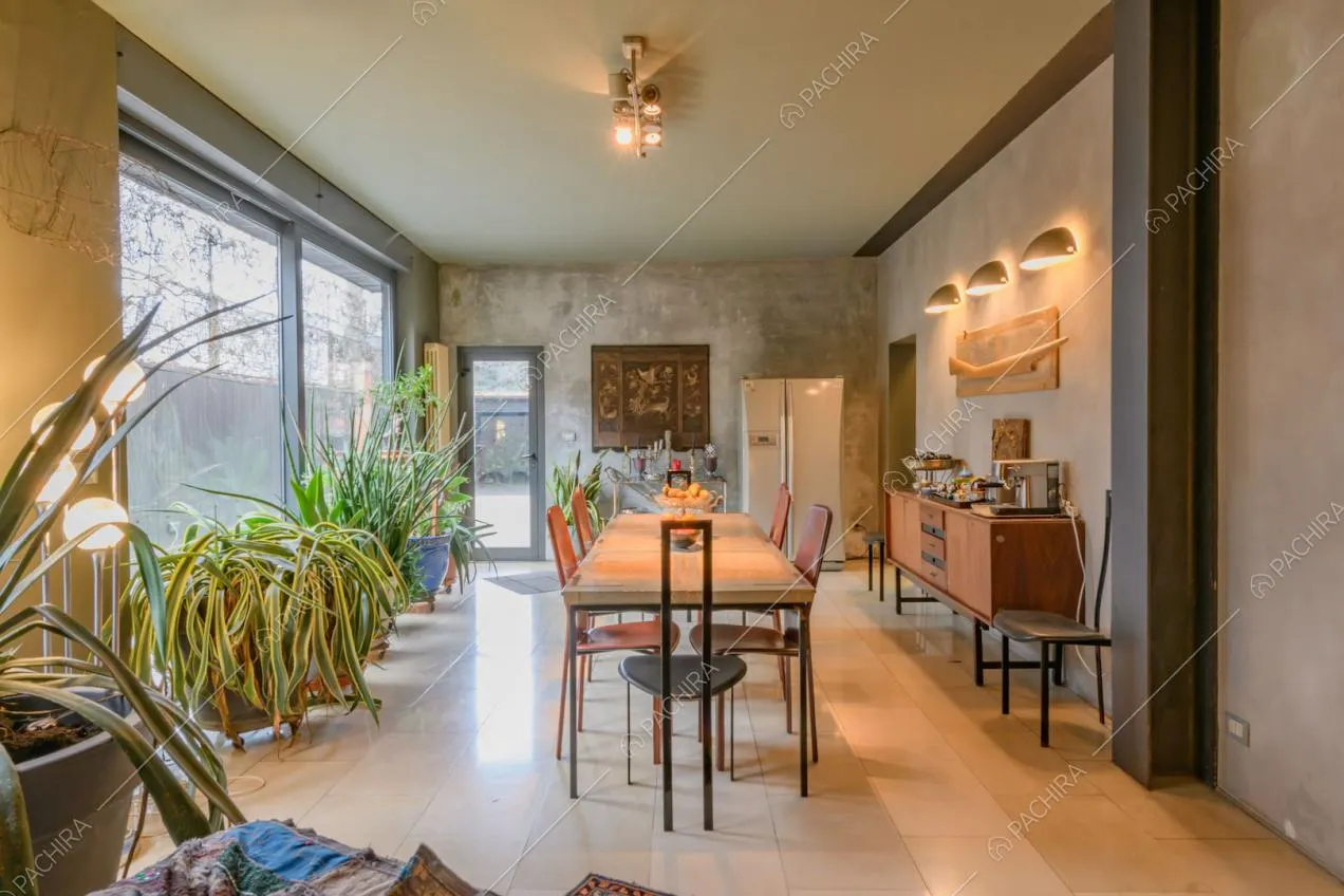 Grande sala da pranzo con ampie vetrate e pareti in stile délabré