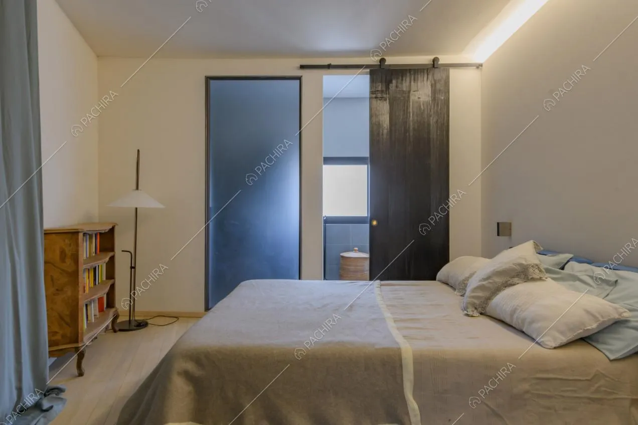 Letto matrimoniale nella camera con pareti bianche e bagno privato