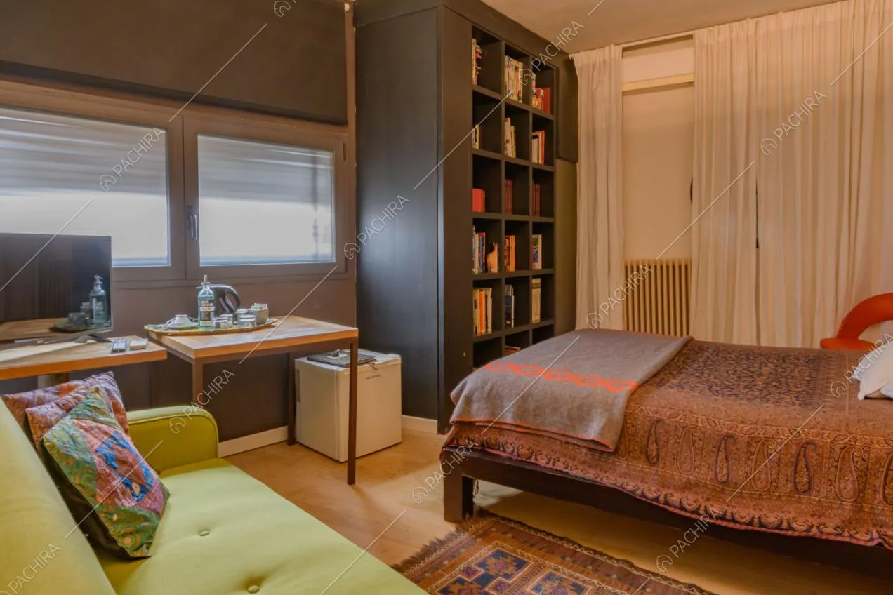 Divano verde, scrivania e libreria nella camera da letto con pavimento in parquet