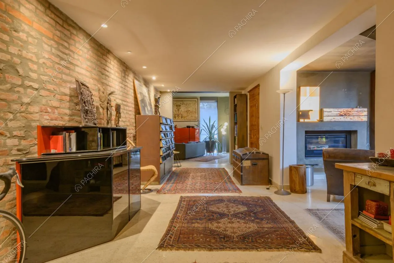 Ampia sala con parete in mattoni a vista, tappeti e mobili di design