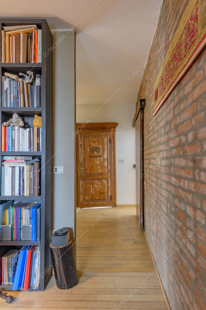 Parete in mattoncini rossi a vista, libreria e pavimento in parquet