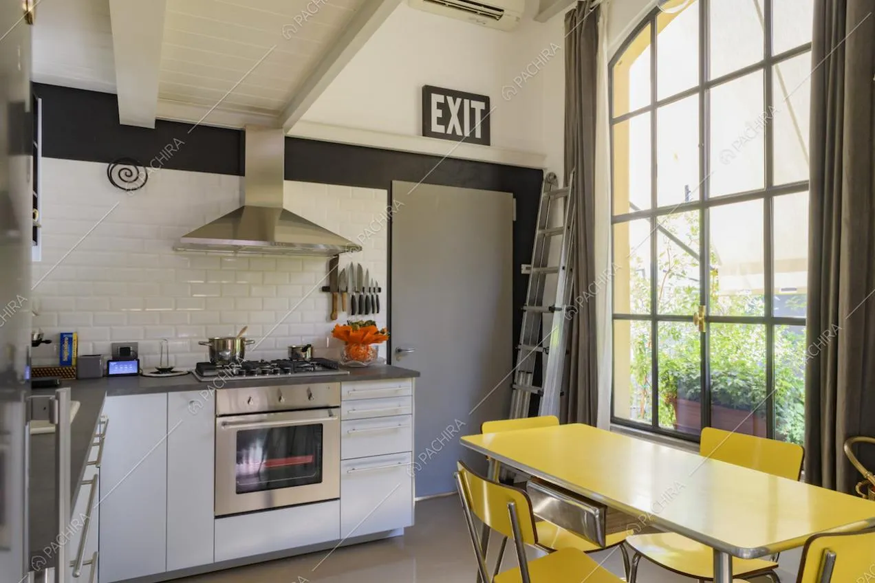 Cucina a vista con mobili bianchi e parete rivestita con piastrelle