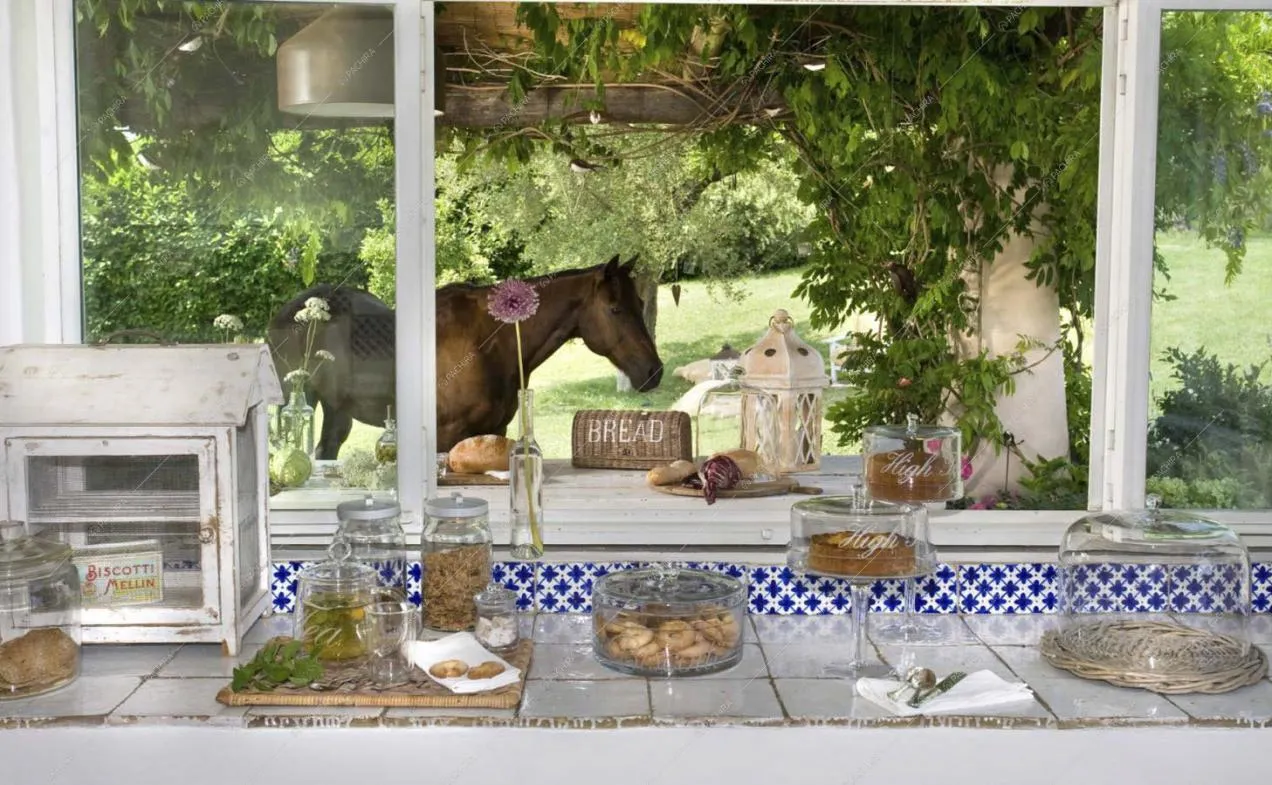 Piano di lavoro della cucina in piastrelle bianche e ampia finestra con vista sul giardino