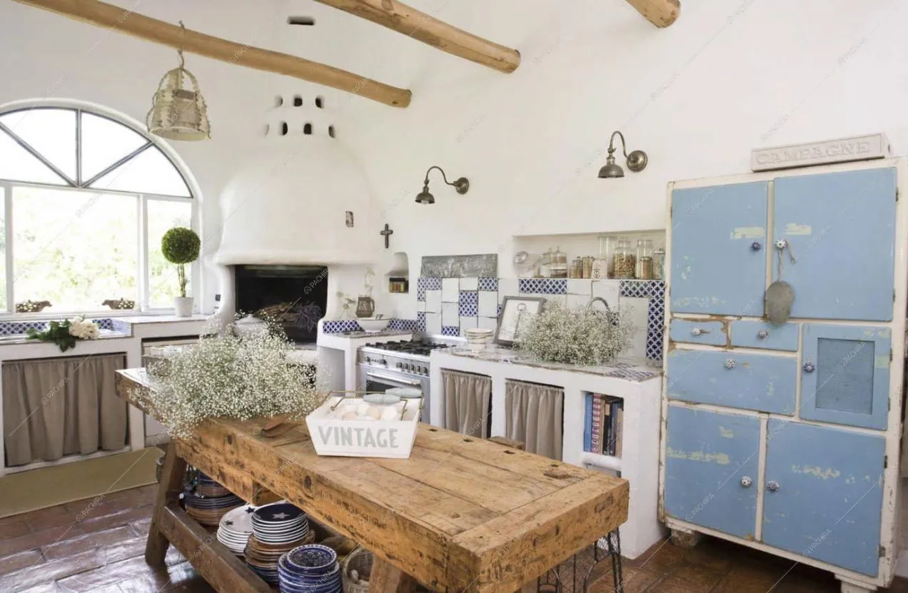 Cucina con travi in legno a vista, soffitto bianco forno a legna e fornelli a gas