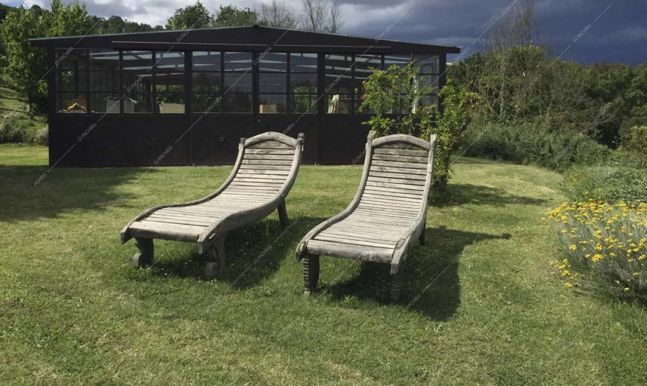 Lettini in legno nel parco davanti alla serra in stile industriale