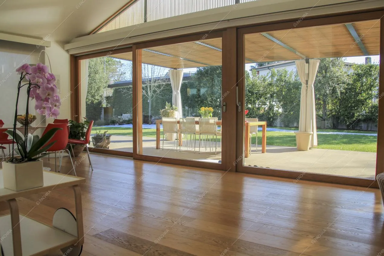 Pavimento in legno e ampie vetrate con vista sul giardino