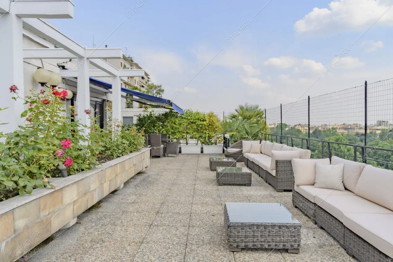 Ampia terrazza con salotto da esterno, numerose piante e vista sul parco