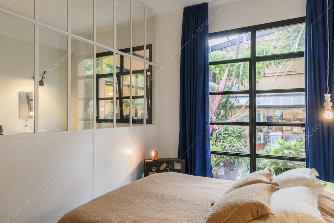 Camera da letto matrimoniale con vetrate bianche che si affacciano sul bagno