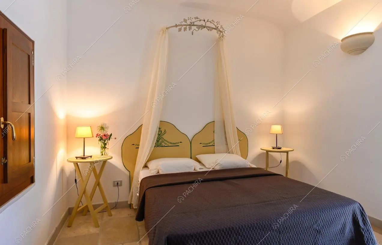 Camera matrimoniale dalle pareti bianche, con letto a baldacchino