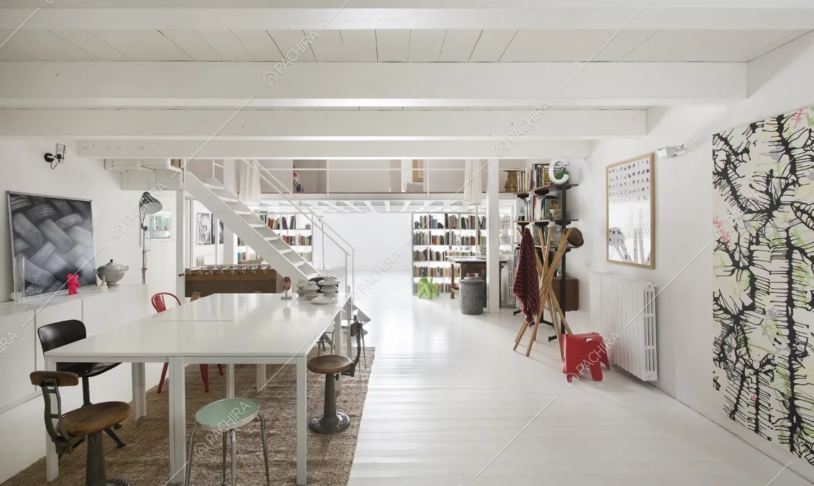 Zona living con tavolo bianco e sedie di modelli diversi