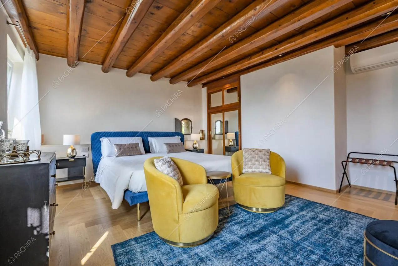 Camera matrimoniale con letto in velluto blu e poltroncine