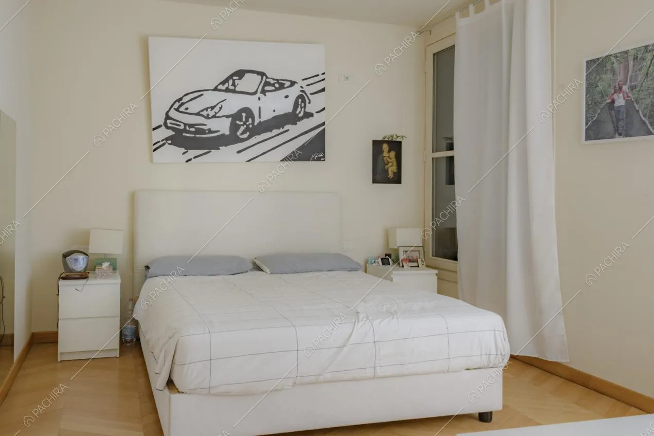 Letto matrimoniale con comodini e stampa in bianco e nero appesa sopra alla spalliera