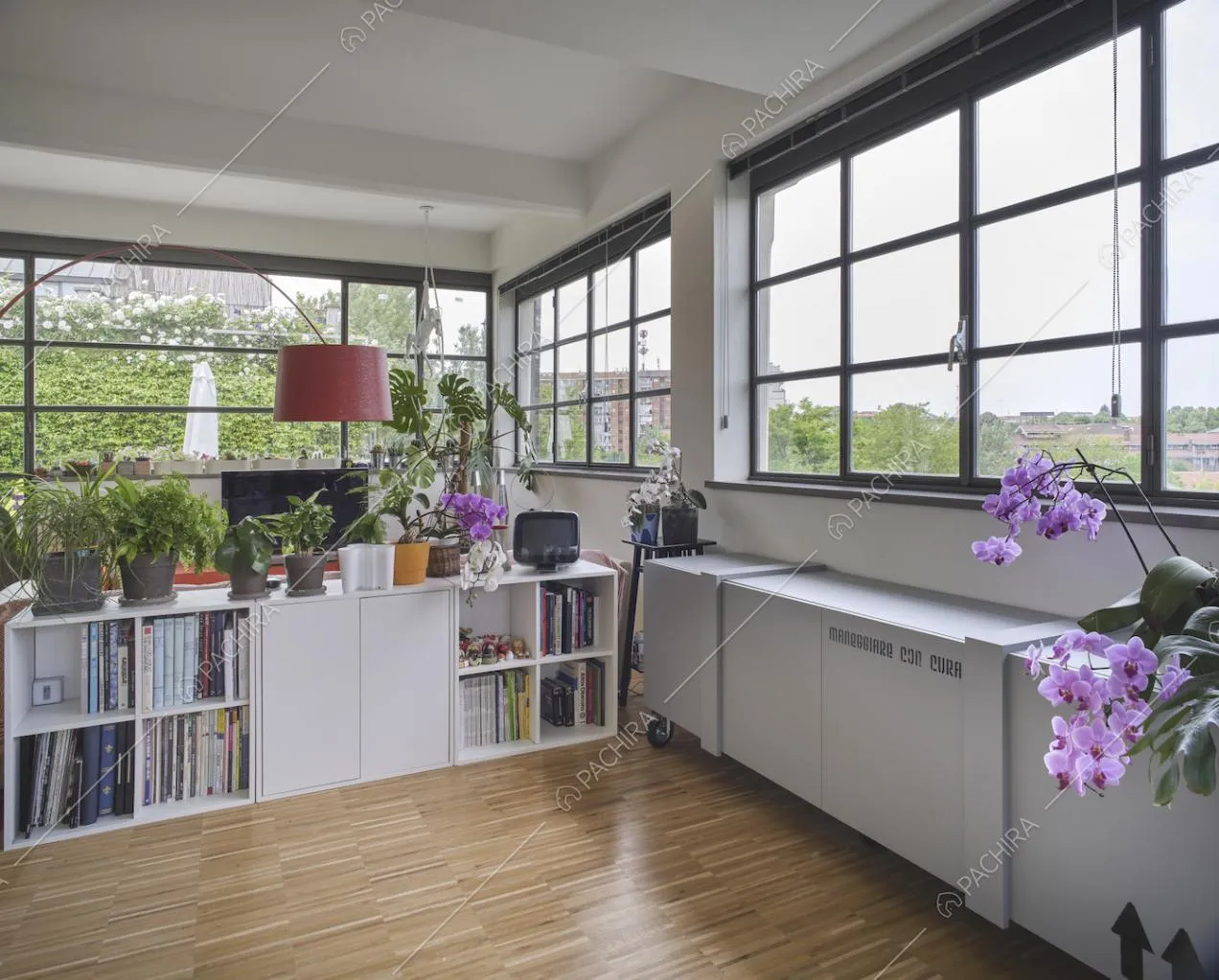 Nella sala, finestre in stile industriale con vista panoramica e lampada di design