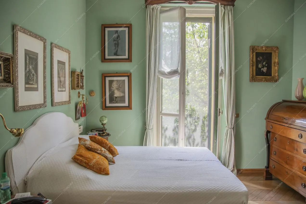 Luminosa camera da letto matrimoniale con pavimento in parquet e pareti verdi