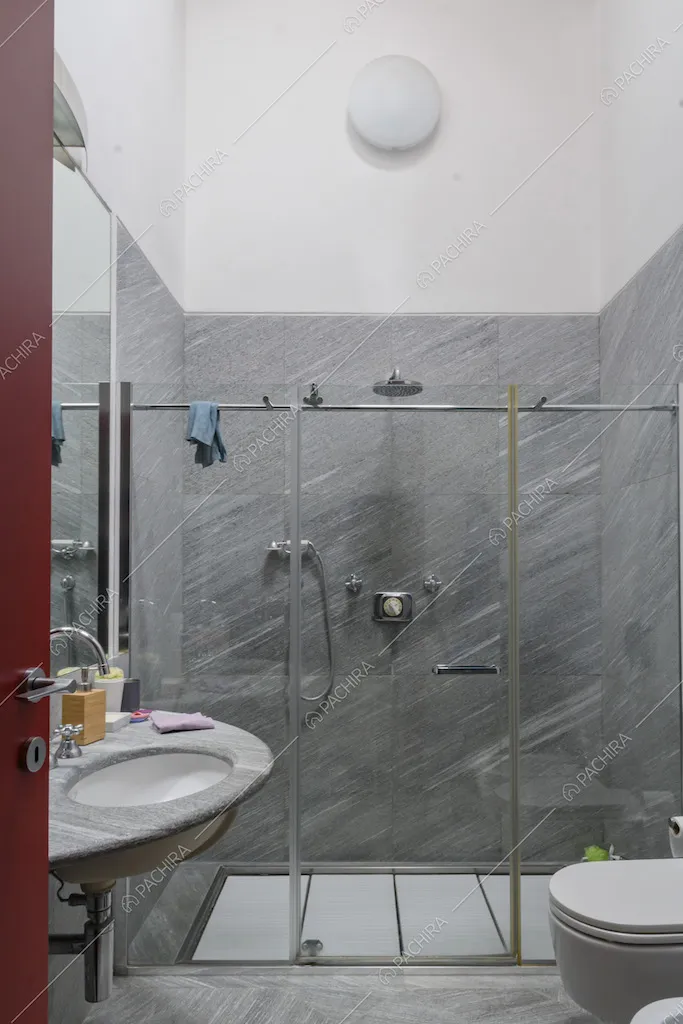Bagno con box doccia e pareti bianche e in pietra