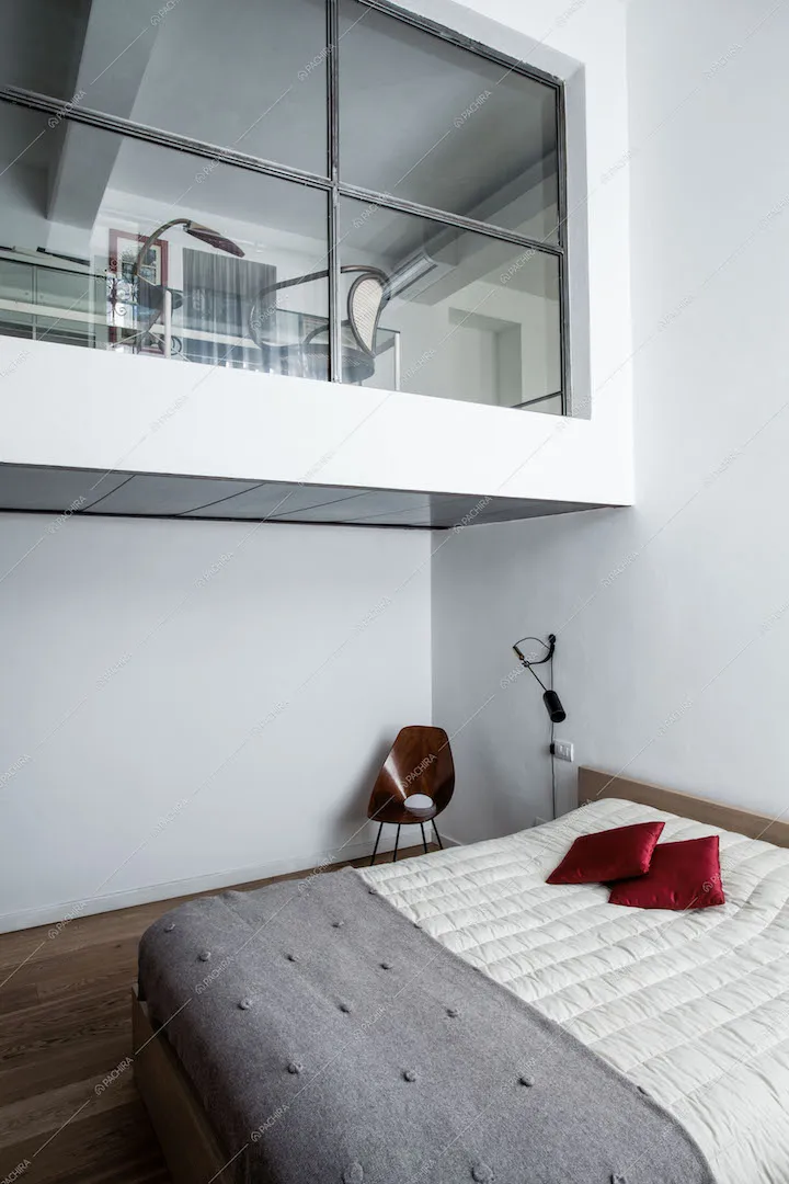 Camera da letto con vista sul soppalco con vetrata