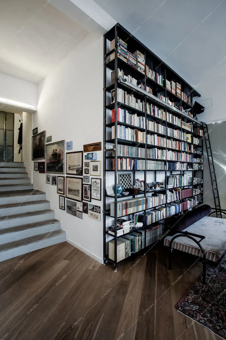 LIbreria a parete con scaletta nera, scale che portano al livello superiore