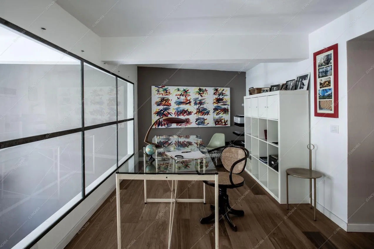 Studio sul soppalco con vetrata, tavolo in vetro e sedia di design
