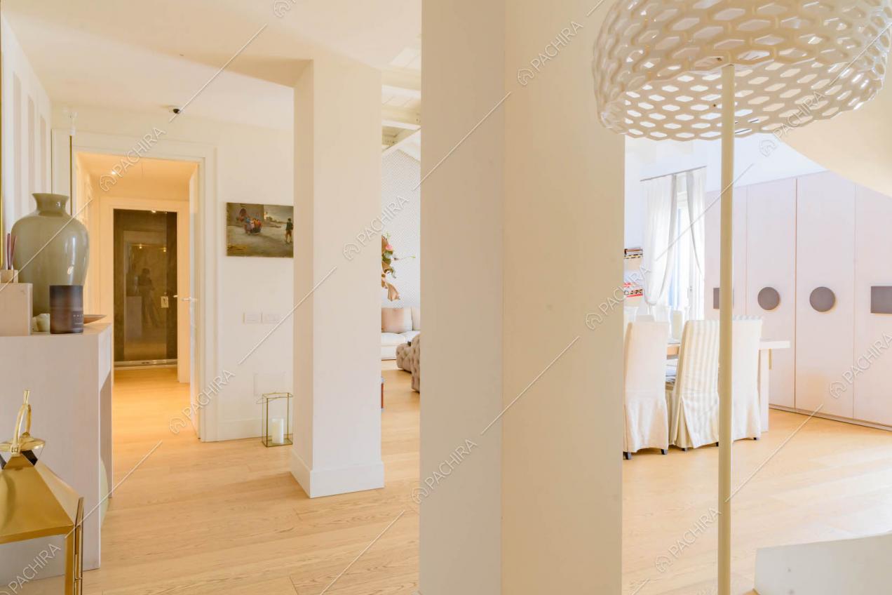 Salone con colonne e pareti bianche, tavolo da pranzo e pavimento in parquet