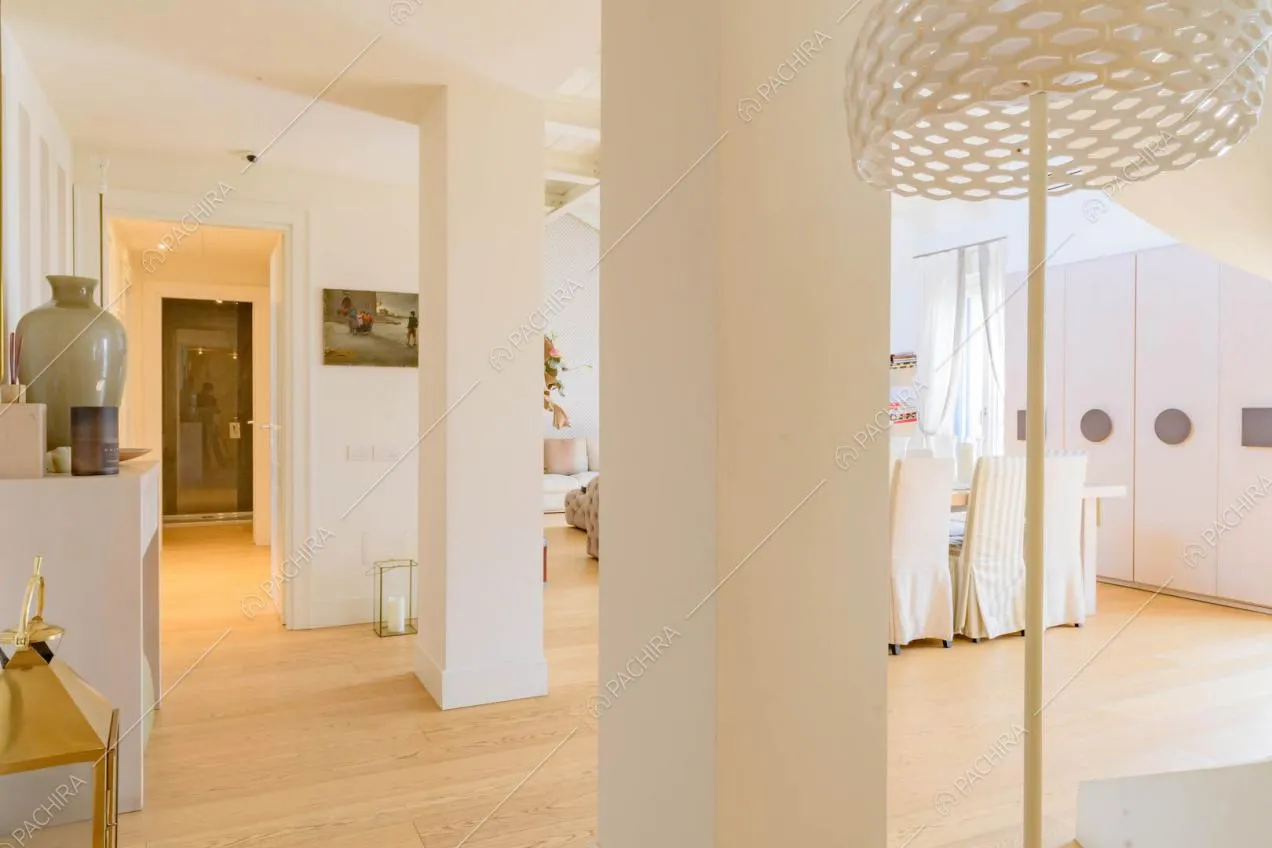 Salone con colonne e pareti bianche, tavolo da pranzo e pavimento in parquet