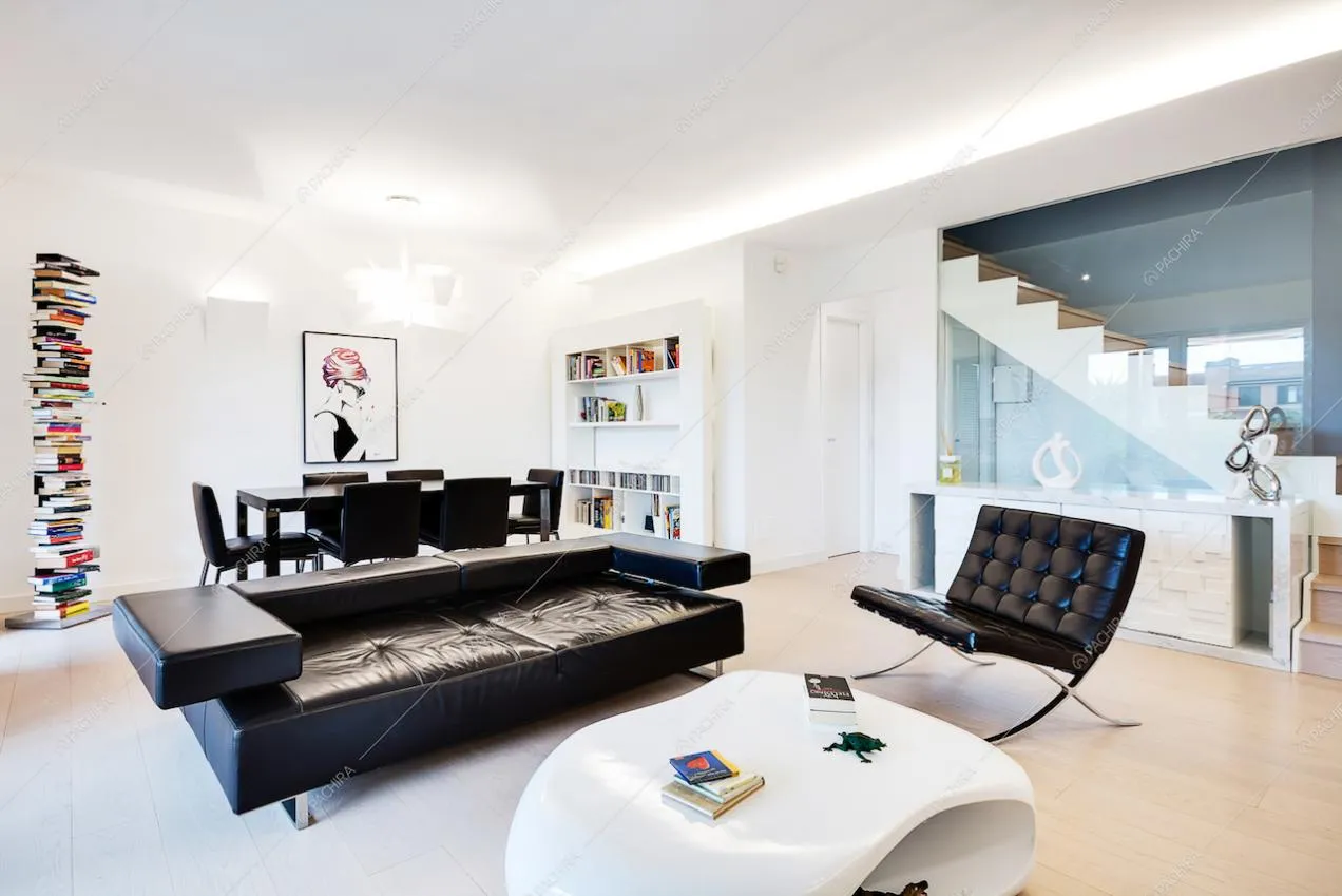 Zona living tavolino bianco, divano e poltrona neri