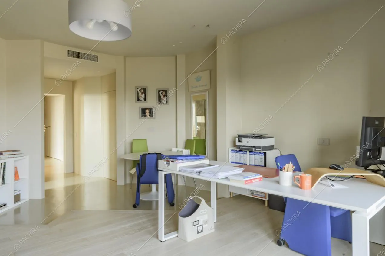 Scrivania bianca dello studio con tavolo e vista sul corridoio