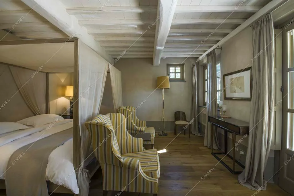 Camera con letto a baldacchino e travi a vista bianche
